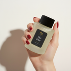 Hand holding a bottle of 'Riviera' with a black cap against a light background