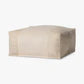 Beige ottoman with a cushion on a neutral background